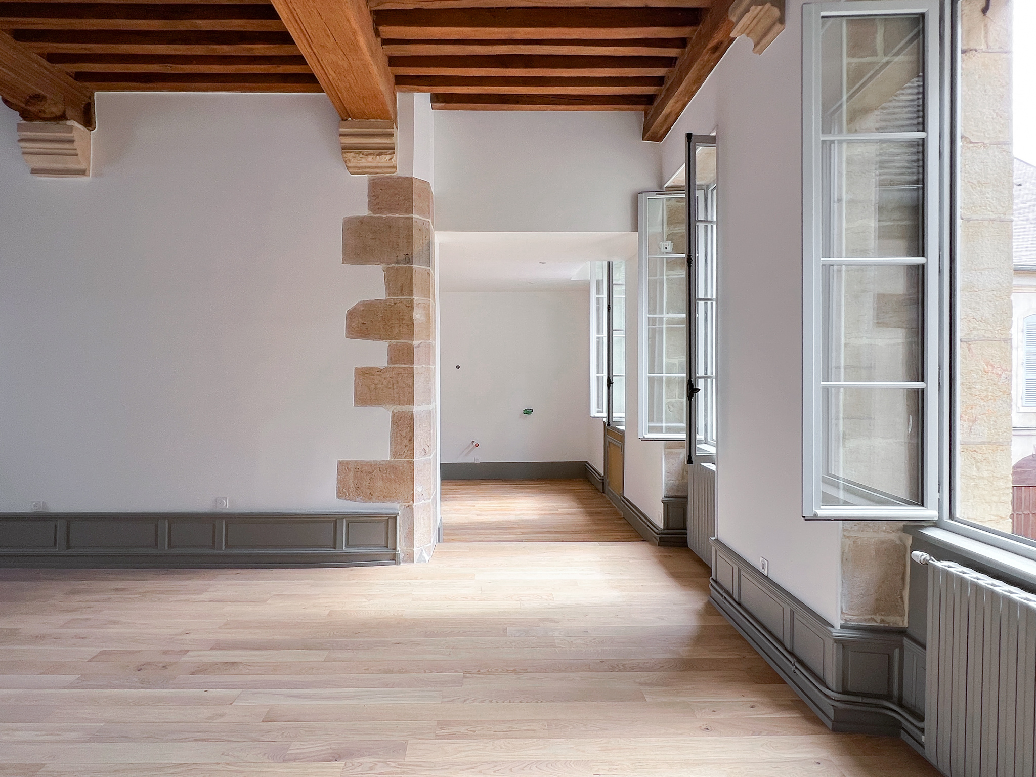 Enfilade des pièces rénovées avec parquet clair et hautes fenêtres