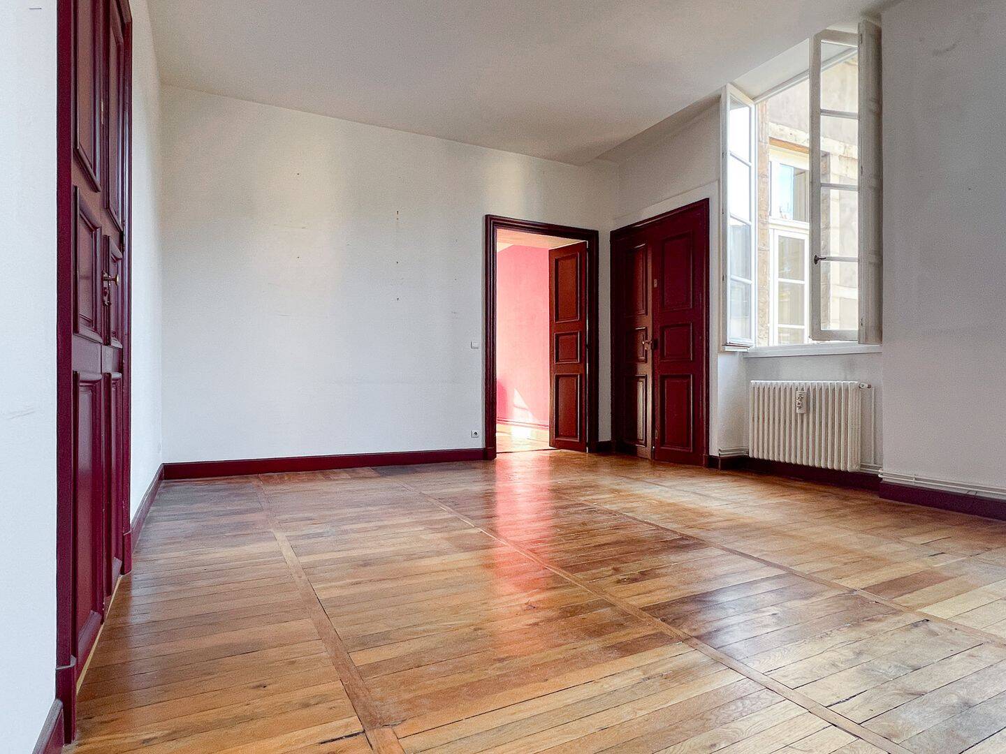 Pièce lumineuse aux boiseries rouges et parquet en chêne