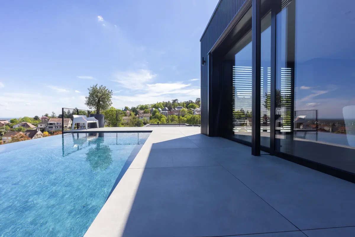 Piscine à débordement le long d'une villa contemporaine vitrée