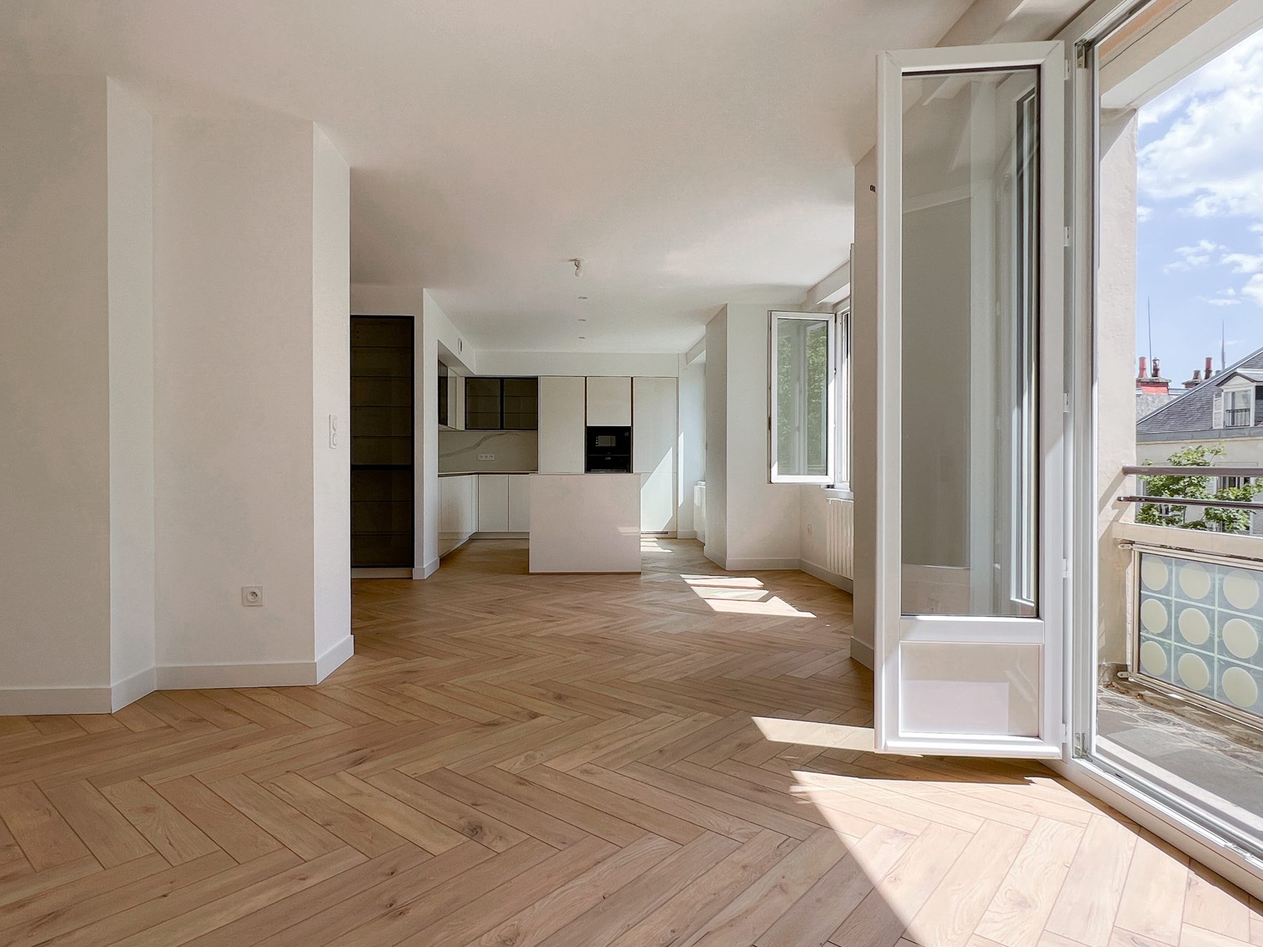 Pièce de vie traversante en parquet à chevrons ouverte sur un balcon, avenue Victor Hugo à Dijon