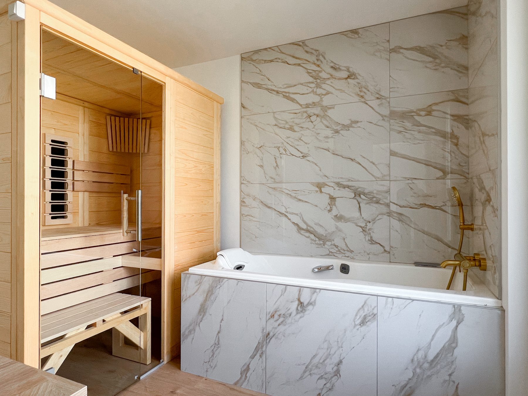 Sauna en bois clair et baignoire balnéo habillée de marbre