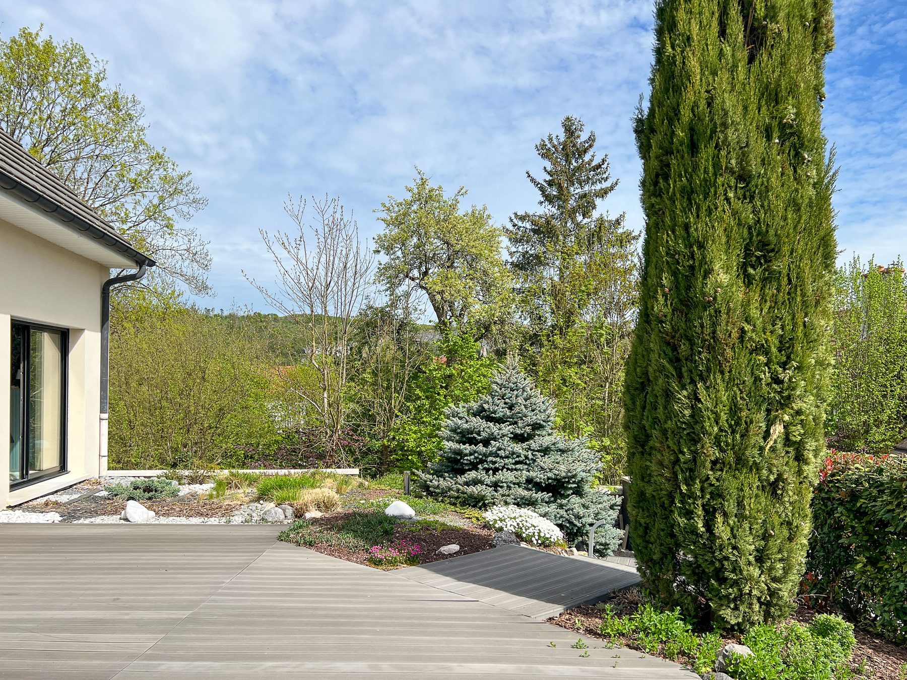 Terrasse en bois et jardin paysagé aux essences persistantes