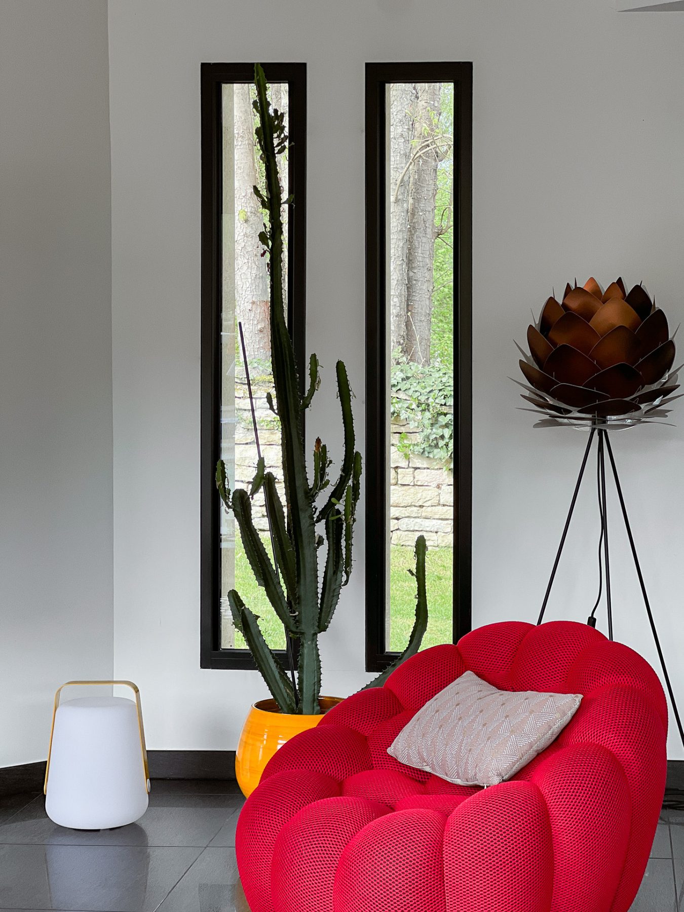 Coin salon avec assise contemporaine devant les hautes fenêtres